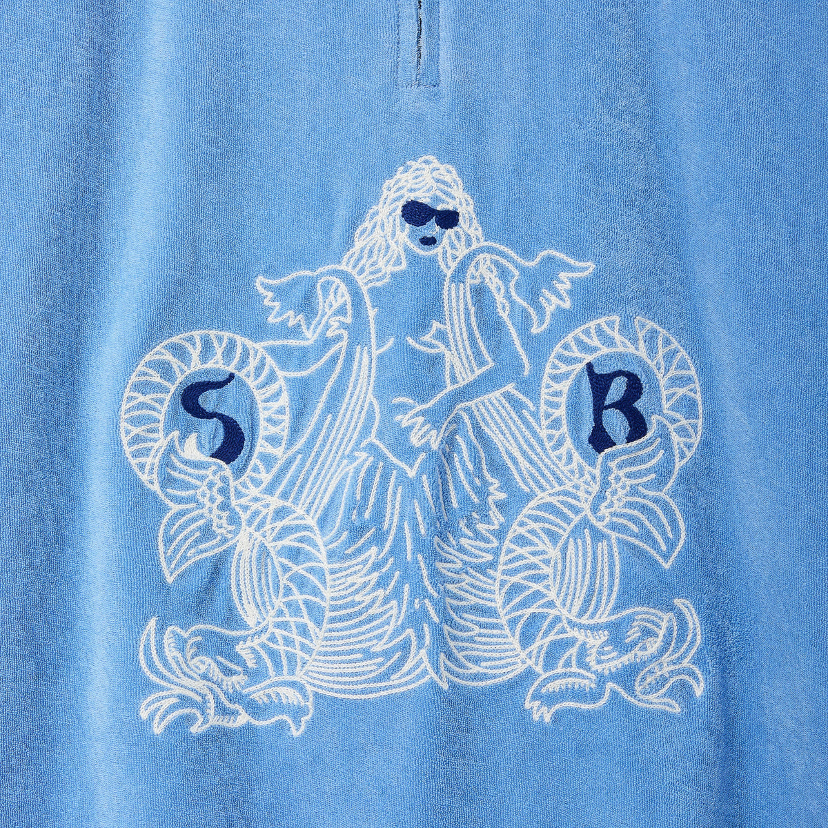 Blue shirt with white mermaid design and 'SR' initials on a blue background