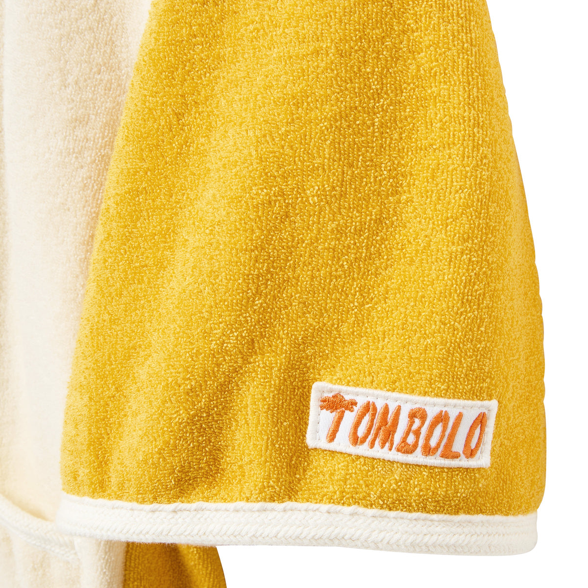 Yellow towel sleeve a white label featuring the brand 'Tombolo' on a white background